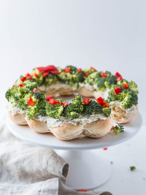 Bread rolls baked into a wreath shape and then smeared with ranch cream cheese and topped with broccoli and red pepper.