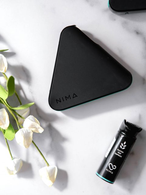 Nima Sensor with flowers and a gluten sensor capsule placed a marble backdrop.