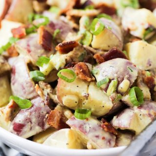 Up close shot of honey mustard potato salad garnished with bacon and green onions.